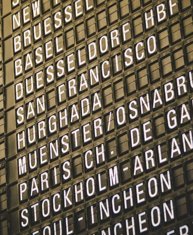 A split-flap airport departure board listing destinations including New York, Brussels, San Francisco, Paris Charles de Gaulle, and Seoul Incheon in white letters.
