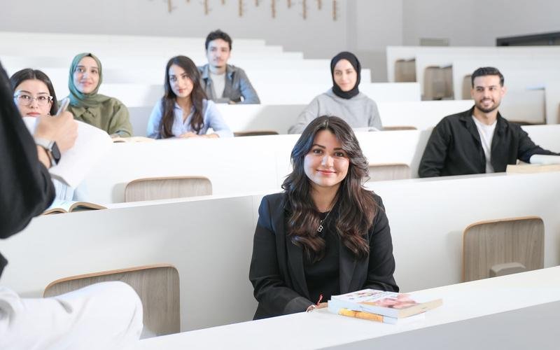 Students seated in a tiered lecture theatre, facing the front of the room