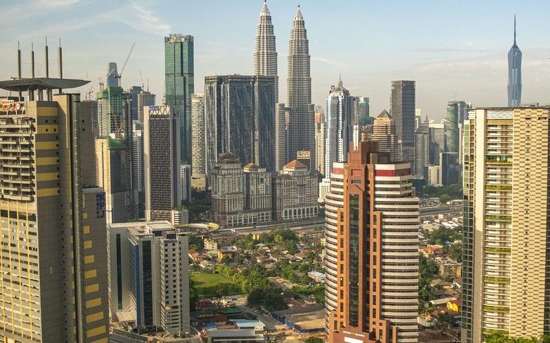 The Kuala Lumpur skyline in daylight, the Petronas Towers standing among the high-rises